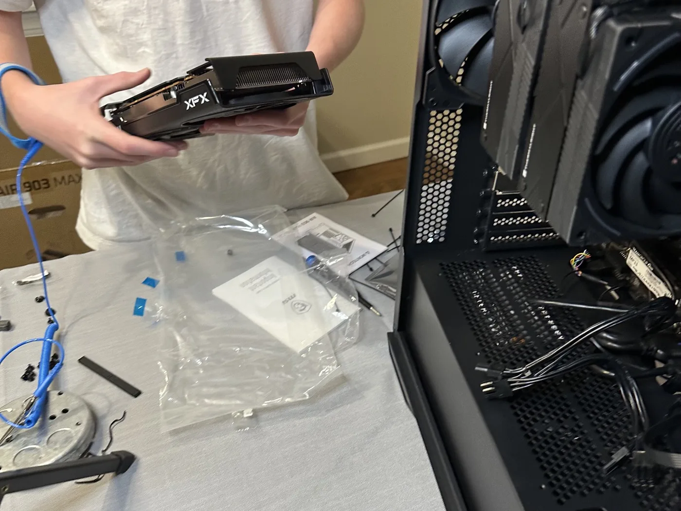 Luca holding an XFX graphics card mid build next to an open PC case